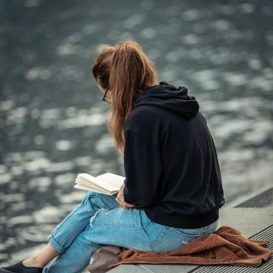 Kvinder sidder ved vandet og læser.