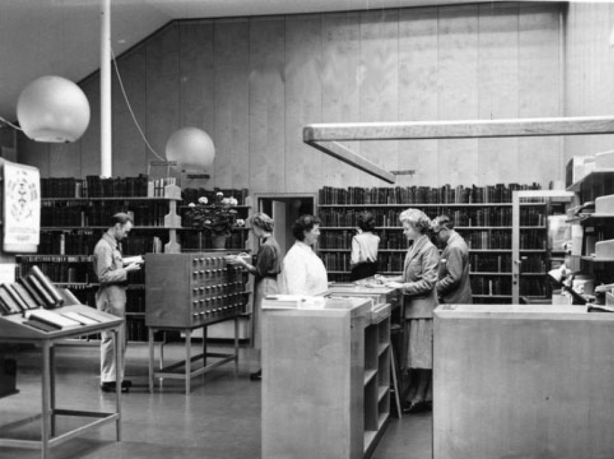 En hverdag på biblioteket. Til venstre ses udstillingspulten, som er et af de originale møbler, der stadig bruges på Nyborg Bibliotek i dag.