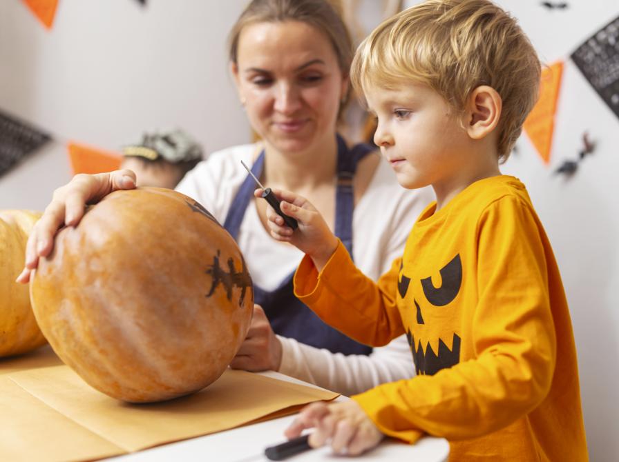 Barn skærer græskarhoved samme med voksen.